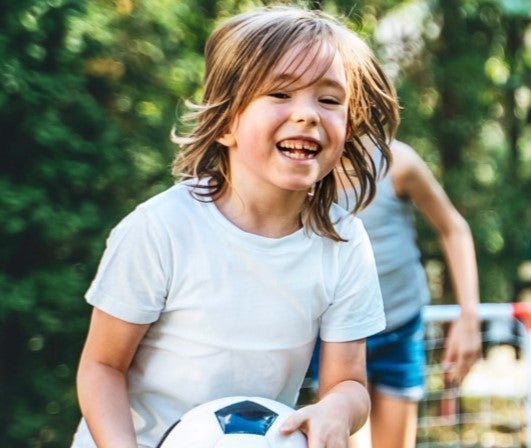 Barn som leker med en boll och ler.